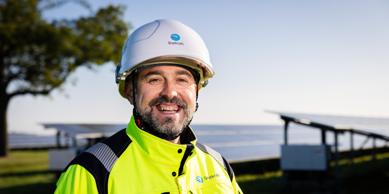 Man smiling wearing safety gear with solar panels in the background