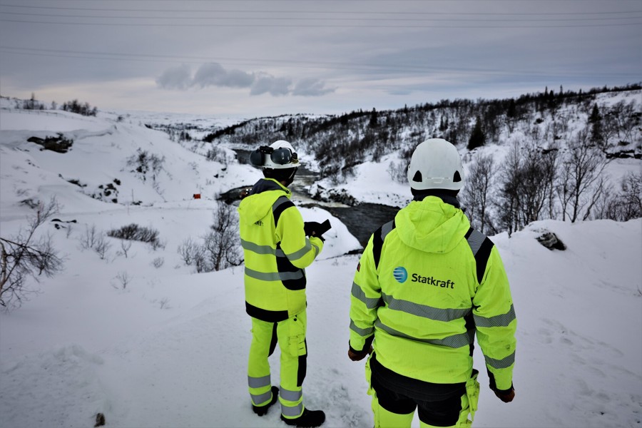Two collegues wearing safety gear on a mountain full of snow